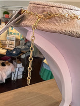 Gold chain accessory on a neck block with a store interior in the background