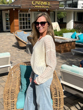 Woman wearing a cream sweater standing outdoors in front of a building with 'Carmel Mission Inn' sign.