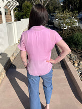 Woman wearing a lilac top and sunglasses outdoors on a sunny day.