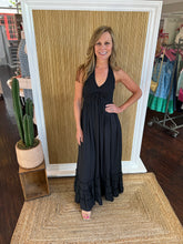 Woman in a black dress standing in front of a mirror with a cactus plant on the floor.