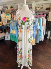 Floral dress on a mannequin in a clothing store with racks of clothes in the background.