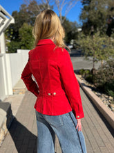 Woman wearing a red peplum jacket and sunglasses outdoors on a sunny day.