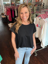Woman wearing a black top and light blue jeans in a clothing store.