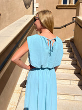 Woman in a blue top and skirt standing on a staircase