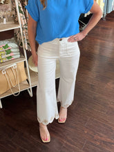 Person wearing a blue top and white pants in a store setting