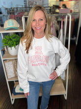 Woman wearing a white sweatshirt with floral and. Fabulous Boutique text in a store setting