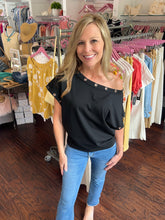 Woman wearing black top that fits off the shoulder. 