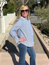 Woman wearing a blue and white striped shirt and sunglasses outdoors.