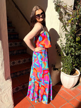 Woman in a colorful strapless dress standing outdoors next to a plant and staircase.