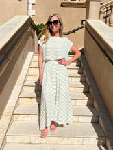 Woman in a striped dress standing on stone steps with a beige building in the background