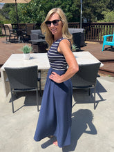 Woman in a striped dress standing on a patio with outdoor furniture.