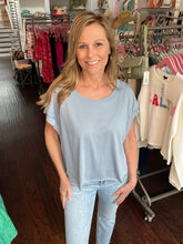 Woman in a clothing store wearing a light blue t-shirt and jeans.