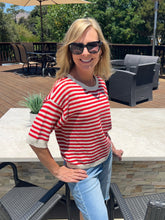 Woman wearing a red and white striped sweater and sunglasses outdoors.