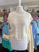 Cream woven sweater on a mannequin in a clothing store setting