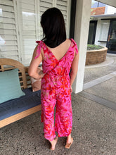 Person wearing a pink floral jumpsuit standing on a patio