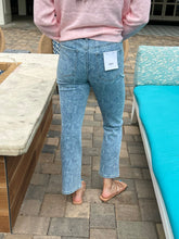 Person wearing light floral print jeans with a tag, standing on a stone patio.