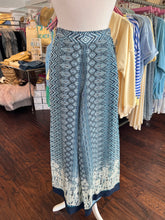 Print pattern palazzo pant on a mannequin in a clothing store with clothing racks behind it.