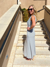 Woman in a blue patterned dress standing on stone steps outdoors.