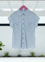 Blue and white striped shirt on a hanger with a blurred indoor background