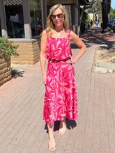 Woman in a pink dress standing on a sidewalk
