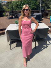 Woman in a red and white striped dress standing on a patio with outdoor furniture.