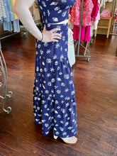 Woman standing in a store wearing a navy seashell print skirt.