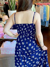 Woman standing in a store wearing a navy seashell print cropped tank top and matching skirt showing the back.