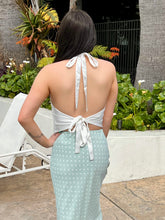 Person wearing a white top and light blue polka dot skirt with a garden in the background