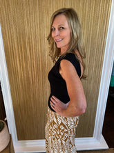 Woman wearing a black top and patterned palazzo pant standing in front of a mirror.