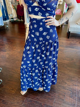 Woman standing in a store wearing a navy seashell print skirt.