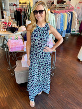Woman wearing a blue printed maxi dress standing in a clothing store.