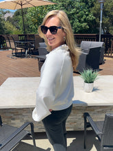 Woman in sunglasses and white blouse standing outdoors on a patio