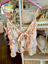 Floral-patterned top hanging on a rack in a store setting with various items in the background.