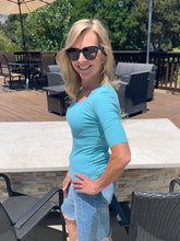 Woman in a blue shirt and sunglasses standing outdoors on a patio.