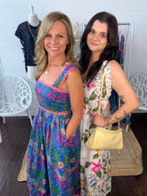 Two women standing in a store, wearing colorful dresses.