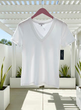 White t-shirt on a hanger with a blurred outdoor background