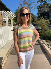 Woman wearing a colorful striped sleeveless top and sunglasses outdoors.
