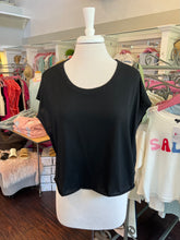 Black t-shirt on a mannequin in a store setting.