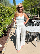 Woman in a white outfit standing outdoors in a garden setting