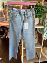 Pair of blue jeans on a pink hanger with a blurred store interior in the background