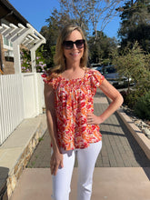 Woman wearing a floral top and sunglasses outdoors on a sunny day.