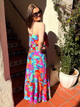 Woman in a colorful strapless dress standing outdoors next to a plant and staircase.