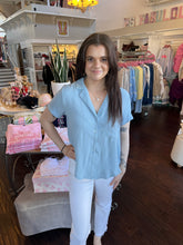 Woman standing in a store wearing a light blue blouse.