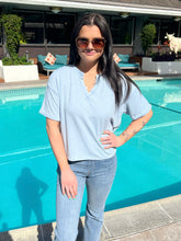 Woman in a light blue shirt and jeans standing by a pool