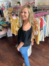 Woman wear black top that is falling off the shoulder.