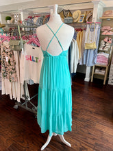 Turquoise dress on a mannequin in a clothing store showing the back view.