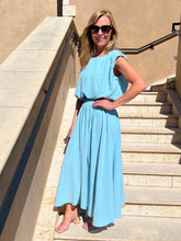 Woman in a light blue dress standing on steps outdoors