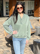 Woman wearing a green sweater and sunglasses outdoors
