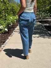 Person wearing blue pants walking on a path with greenery in the background