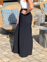Person wearing a black skirt with a white top in an outdoor setting.